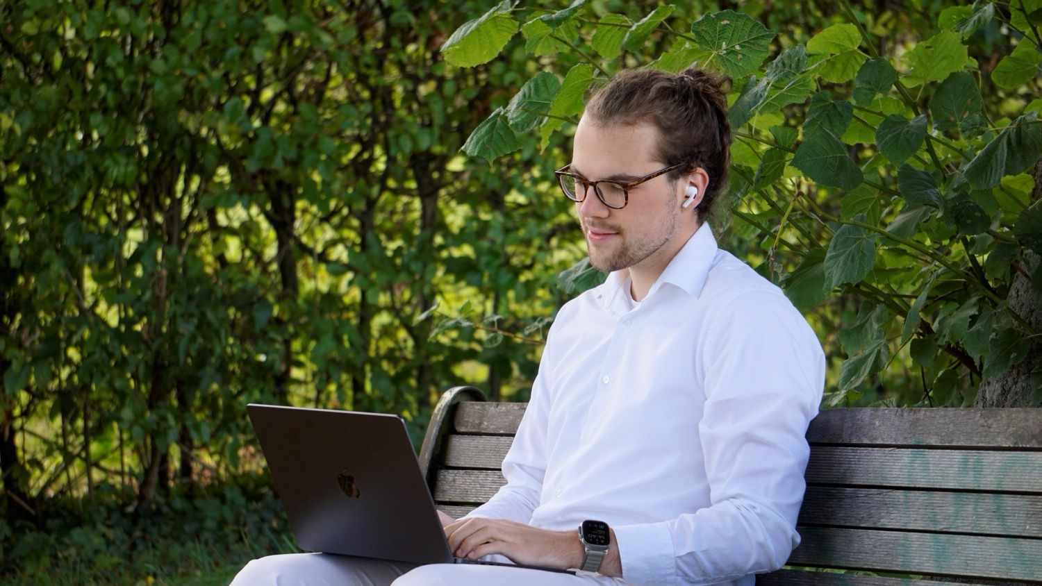 Ein IT-Experte arbeitet remote mit einem Laptop auf einer Parkbank